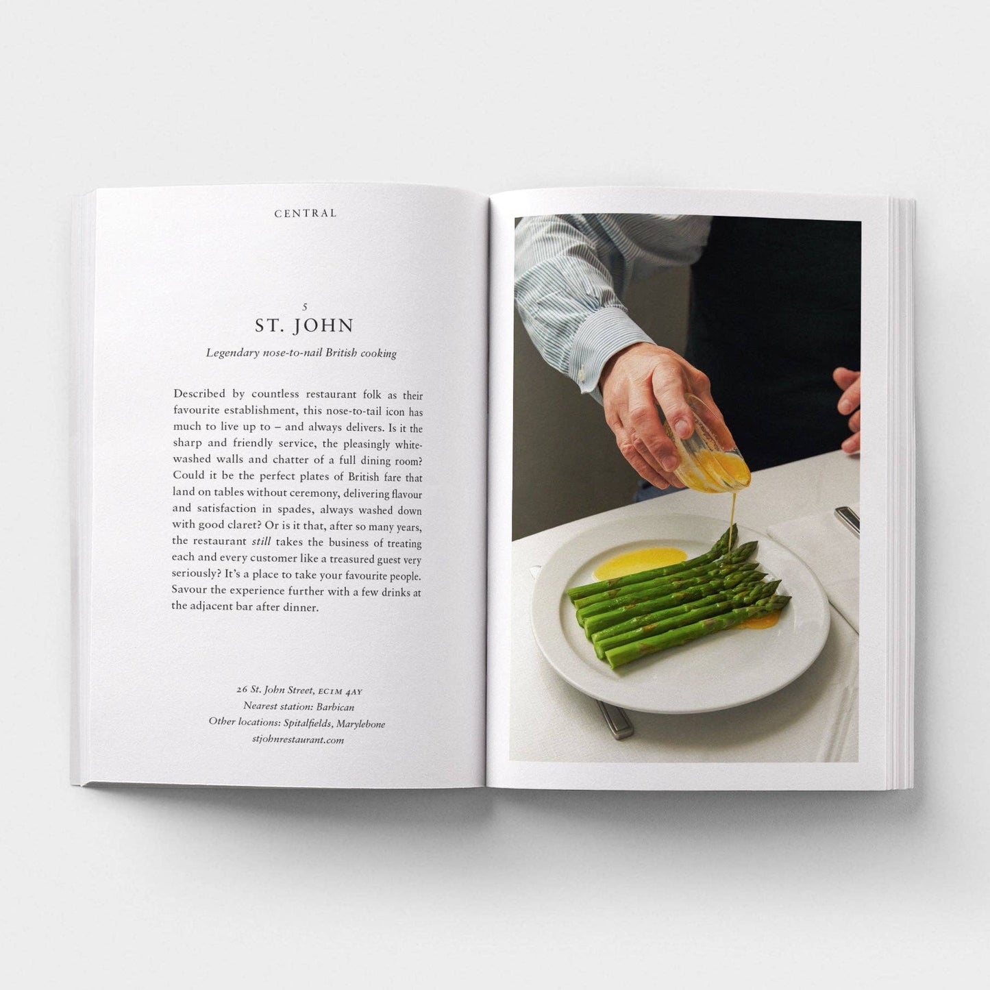 Open book showing a recipe for asparagus with a person garnishing it.