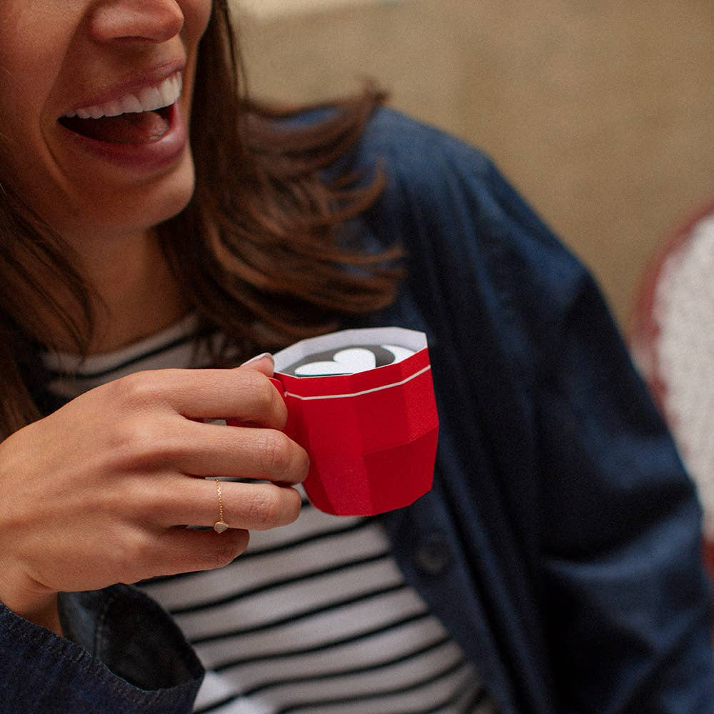 Person holding a red mug with a striped shirt and blue jacket