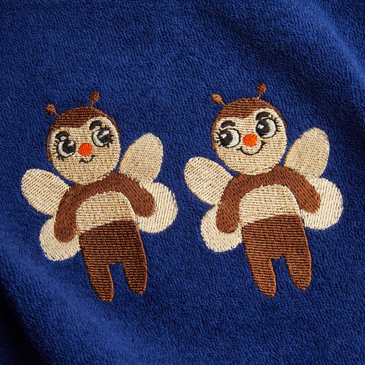 Two embroidered bee designs on a blue fabric background