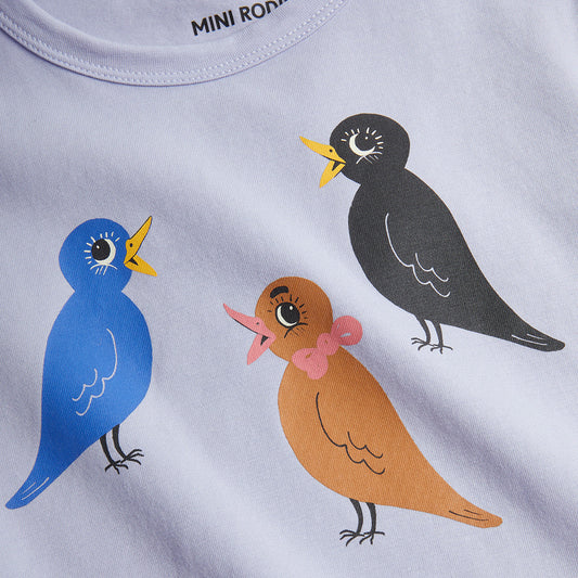 Close-up of a t-shirt with colorful bird illustrations on a light gray background.