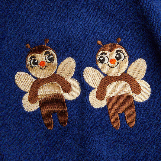 Two embroidered bee designs on a blue fabric background