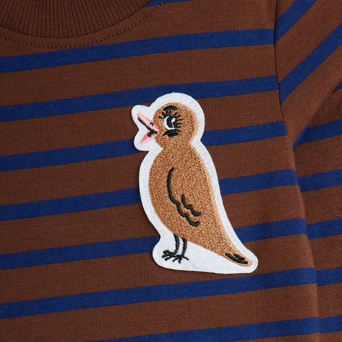 Brown and blue striped shirt with a bird patch