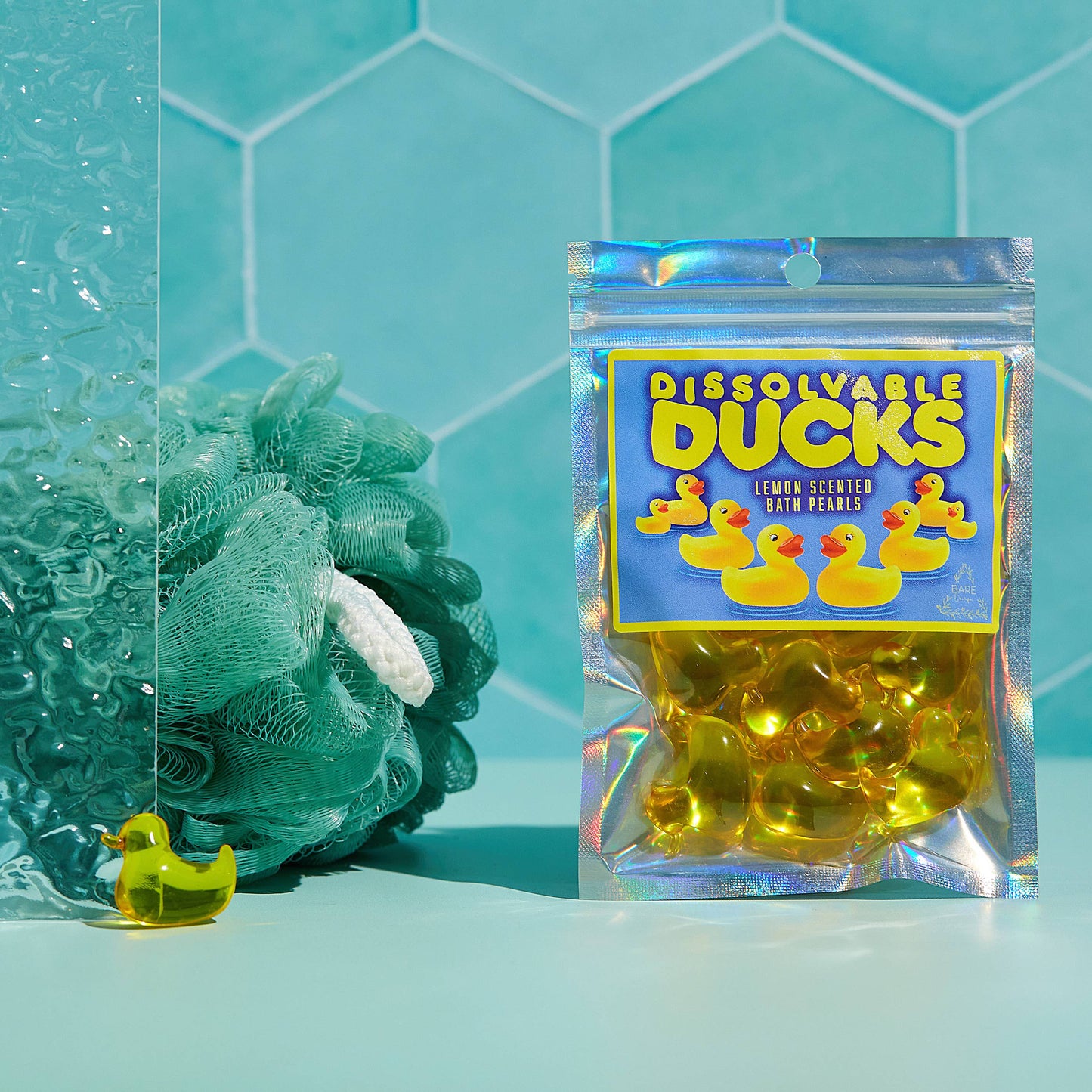 Packaged product labeled 'Dissolvable Ducks' with a green sponge and yellow duck toy on a teal tiled background.