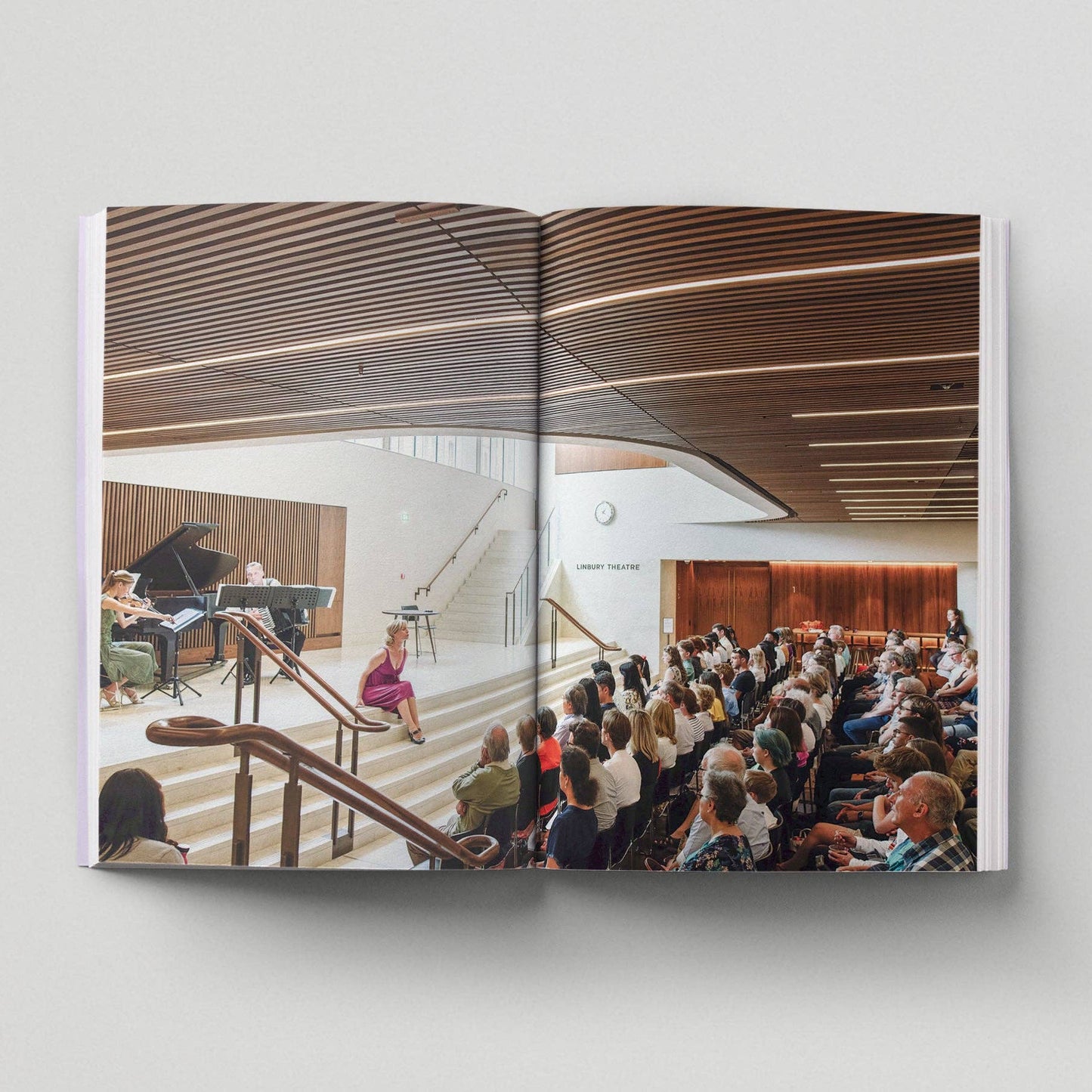 Open book showing an interior view of a concert hall with people in attendance.
