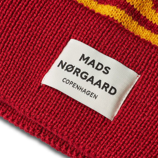 Red knitted product with a Mads Nørgaard label on a white background