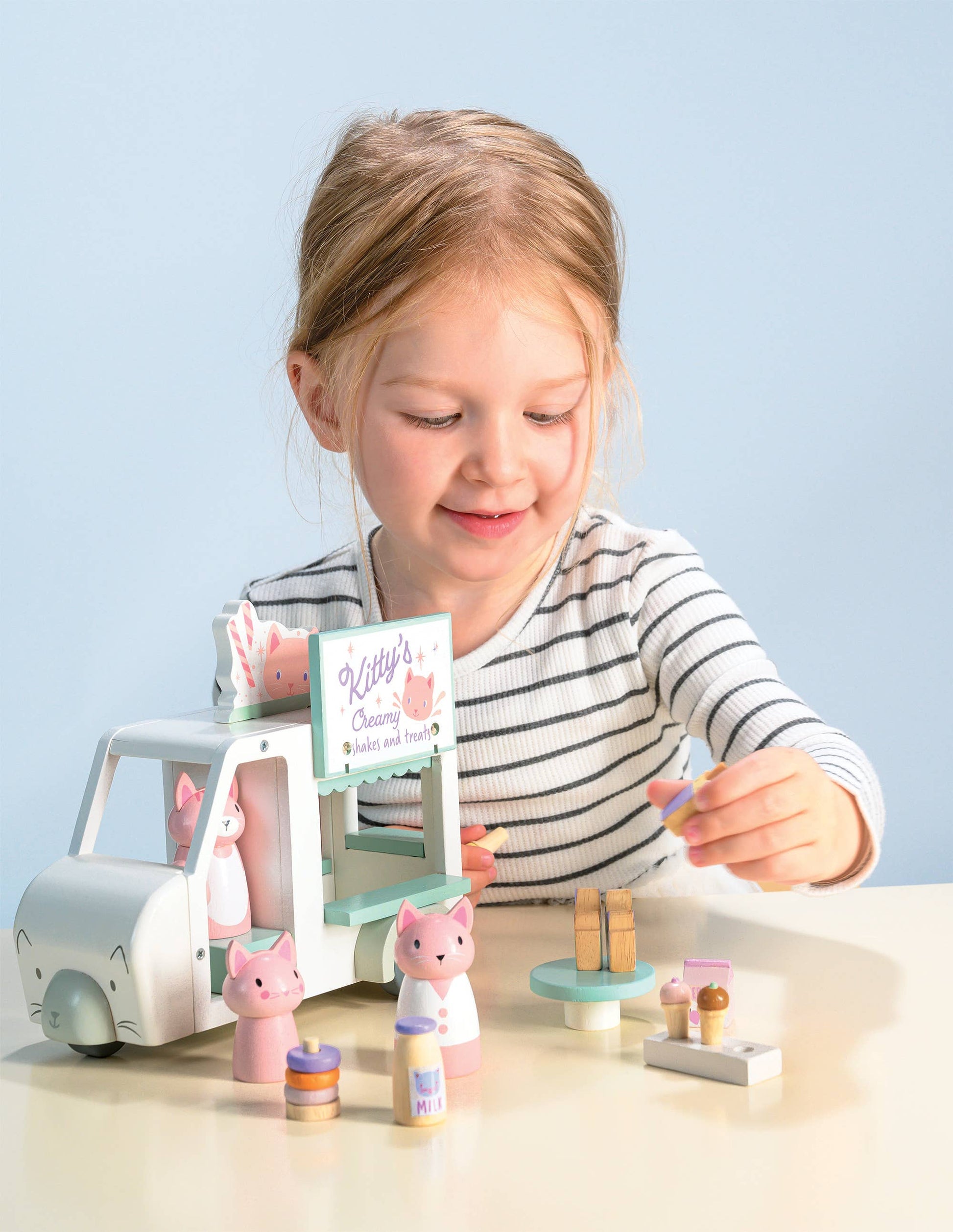 Child playing with a wooden toy set on a light blue background