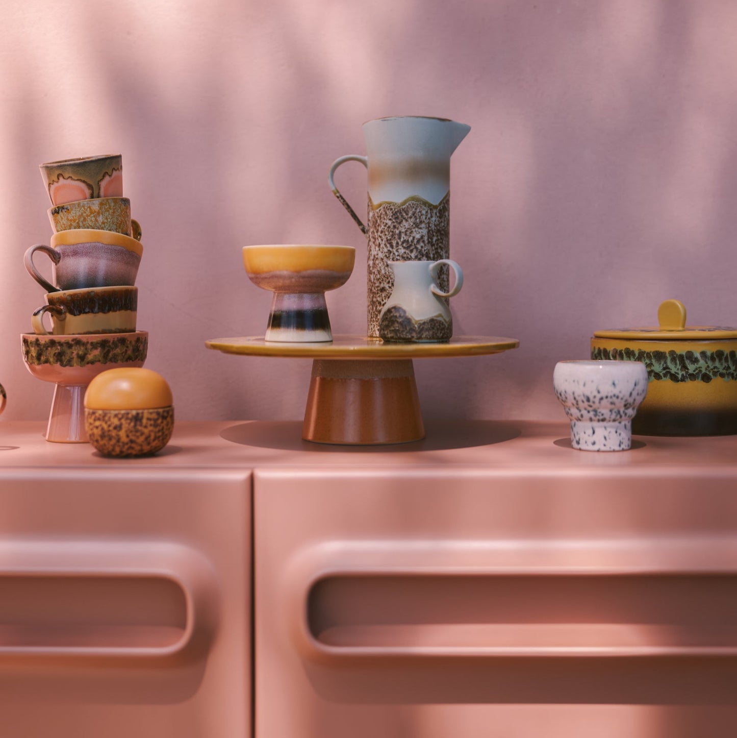 Collection of ceramic items on a pink surface with a soft pink background