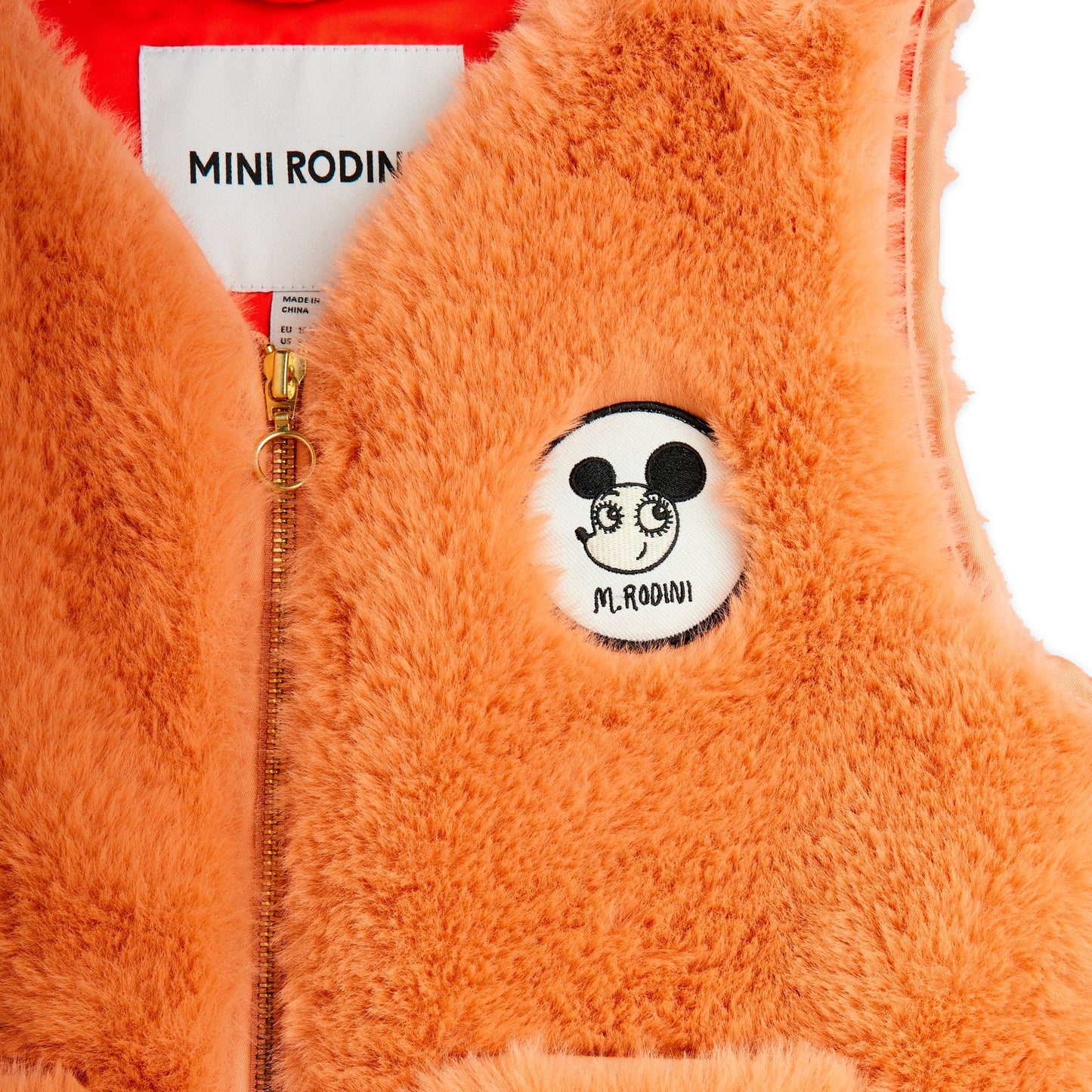 Orange fluffy vest with a brand logo patch on a white background