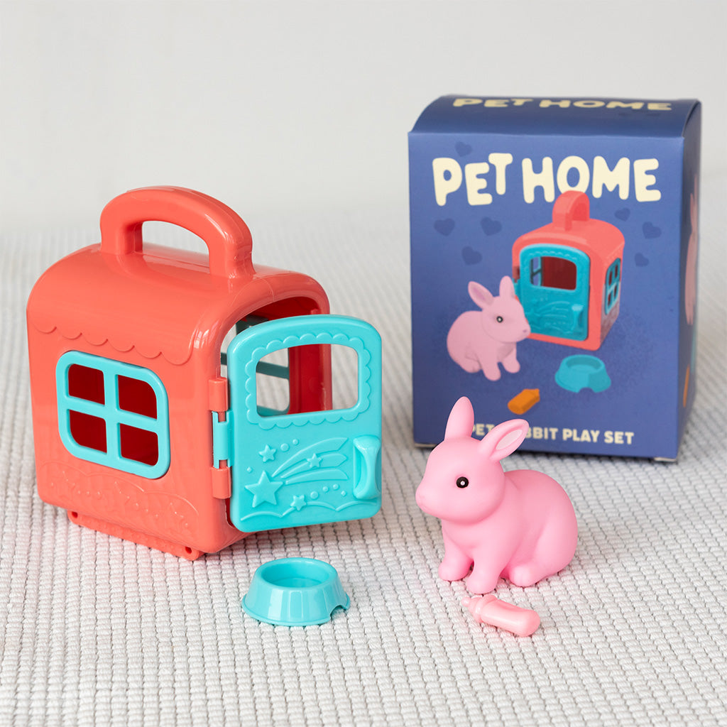 Toy pet house with pink rabbit figure and packaging on a textured surface