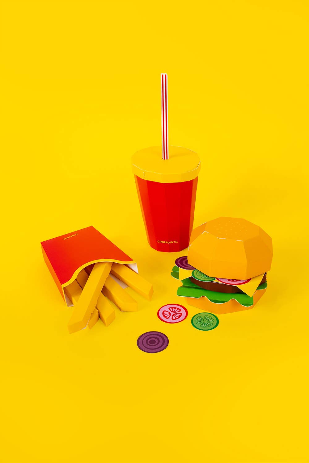 Colorful drink cup with straw, burger, and fries on a yellow background