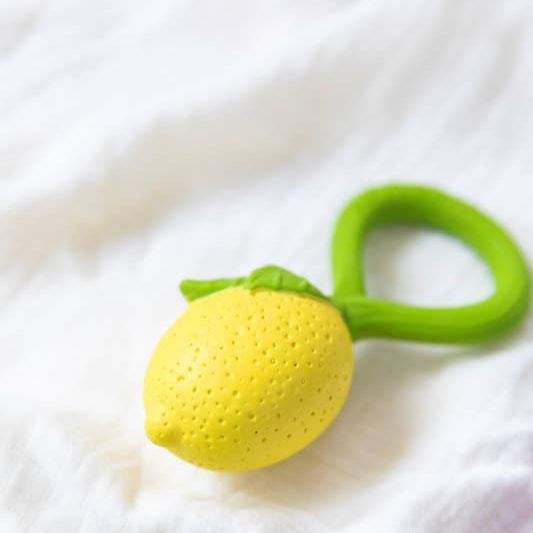 Yellow teething ball with green handles on a white fabric background