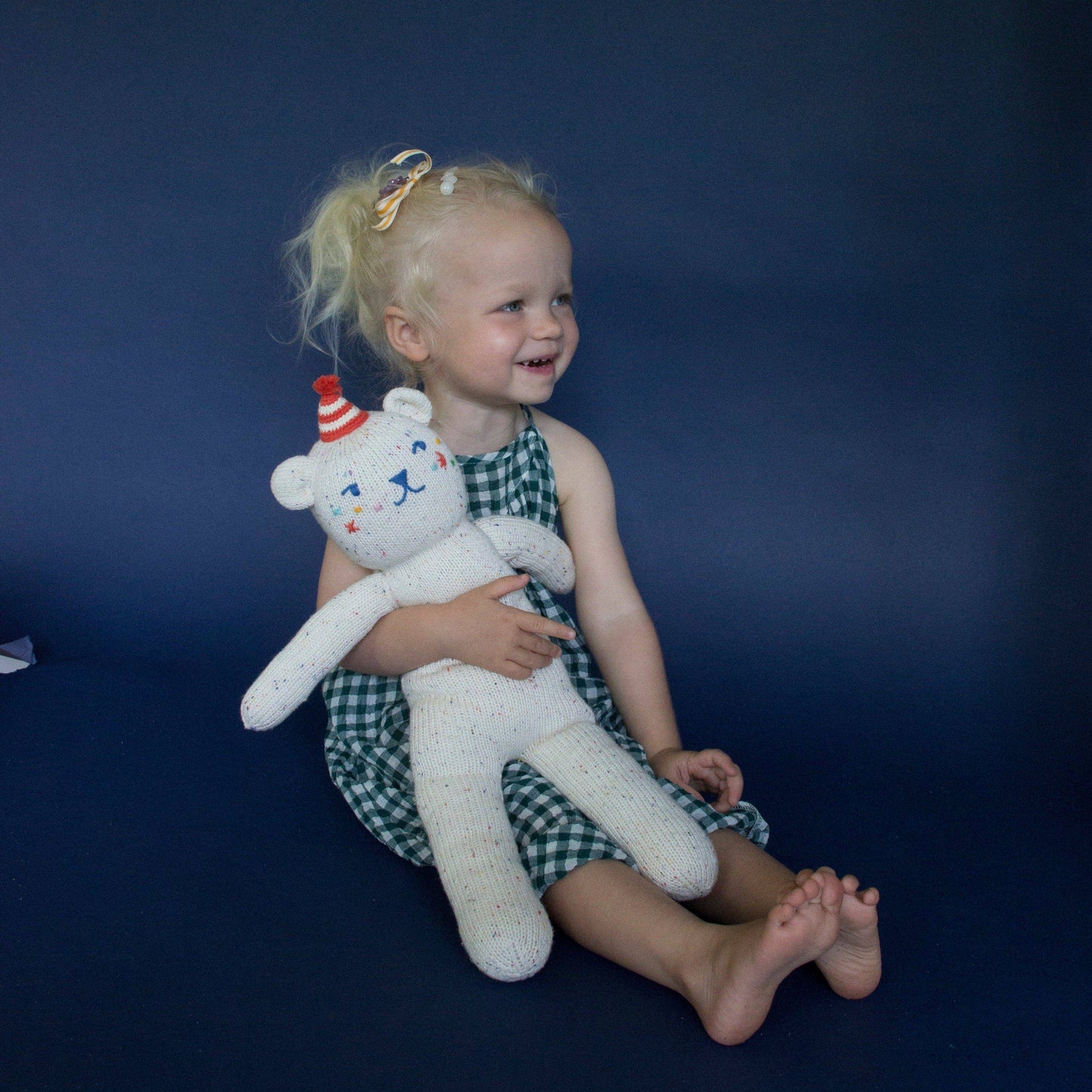 Child holding a teddy bear against a dark blue background