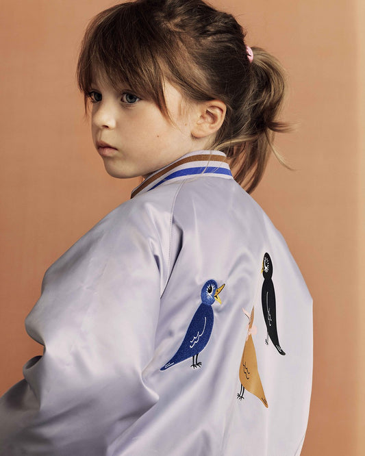 Child wearing a white shirt with cartoon birds on a brown background