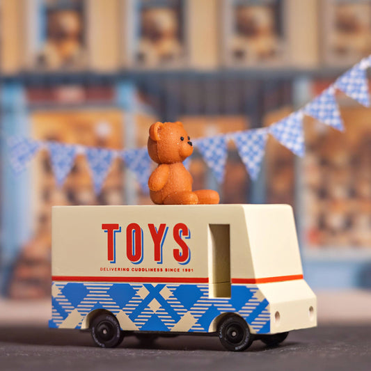 Toy truck with a teddy bear on top against a blurred toy store background