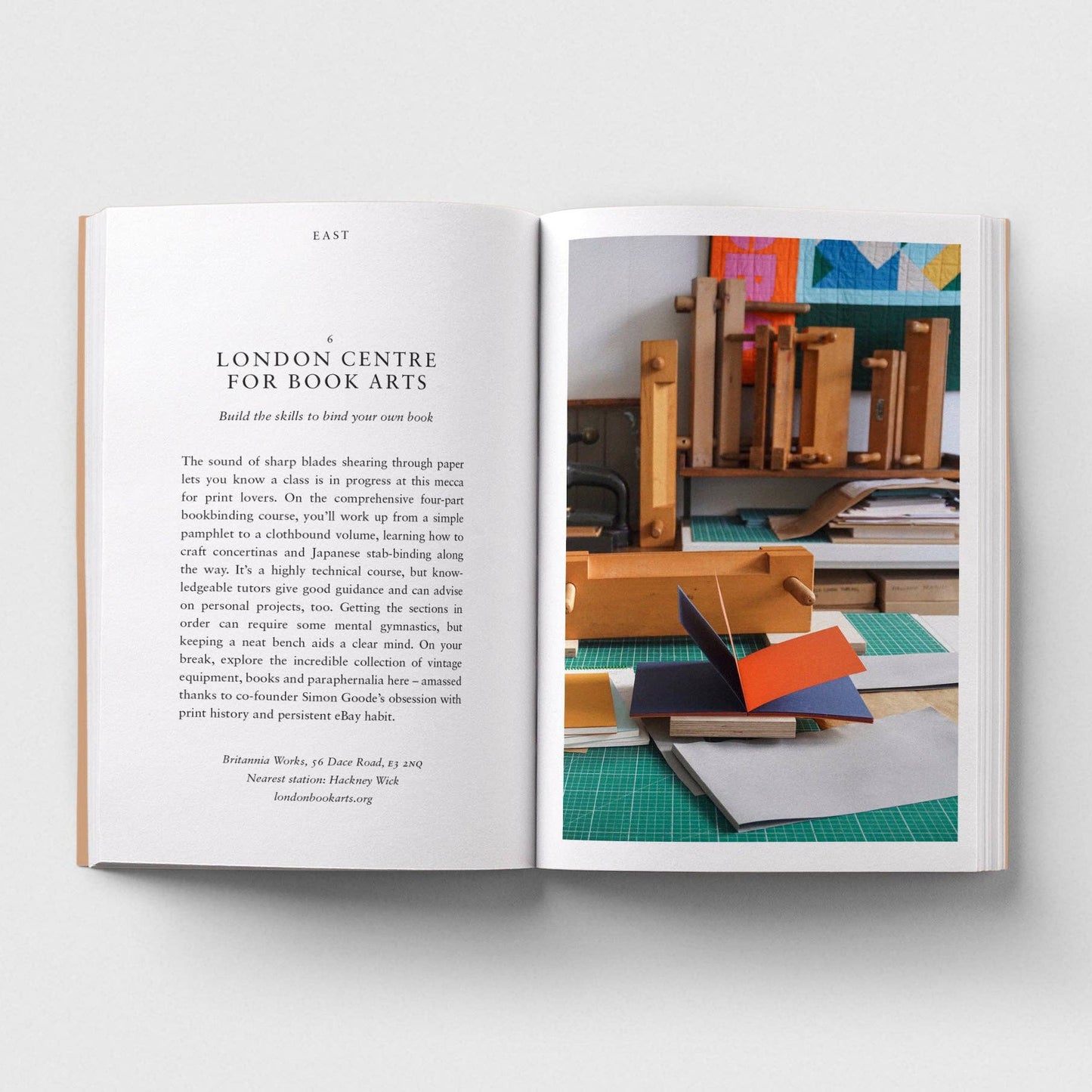 Open book showing text and a photograph of a workspace with books and materials.