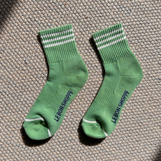 Pair of green socks with white stripes on a textured surface