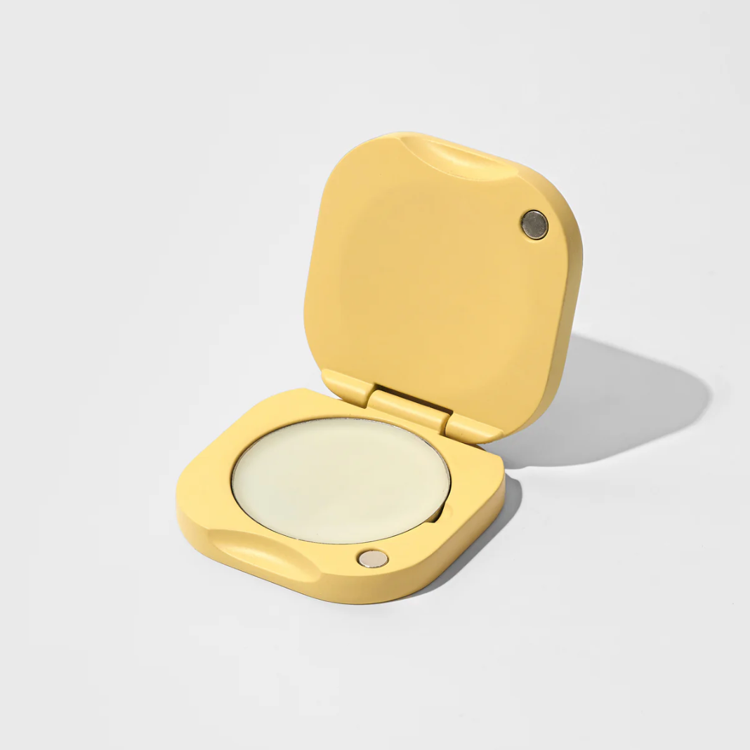 Gold compact powder case with open lid on a light gray background