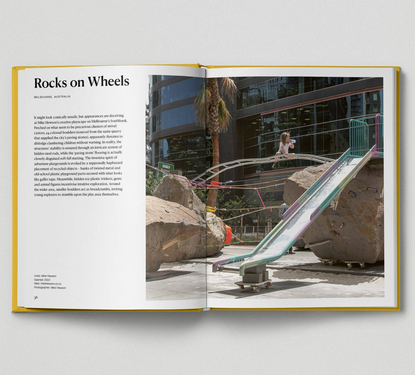 Open book showing a photograph of a playground with rocks and a slide, and text on a white background.