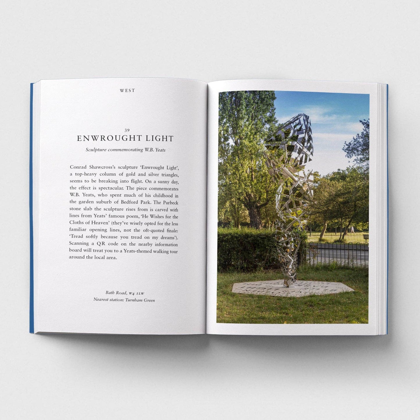 Open book with text on one page and an image of a sculpture on the other, set against a white background.