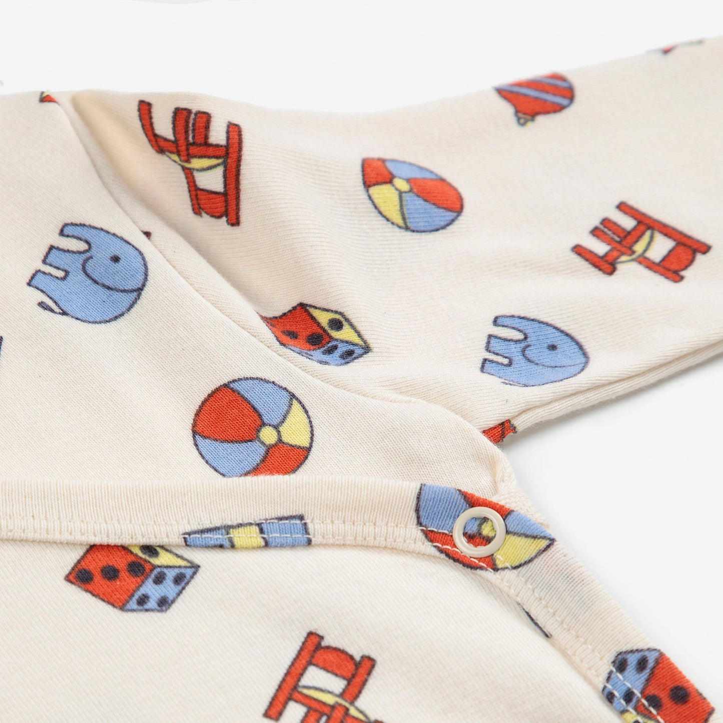 Close-up of a cream-colored fabric with colorful geometric patterns including elephants, circles, and houses.