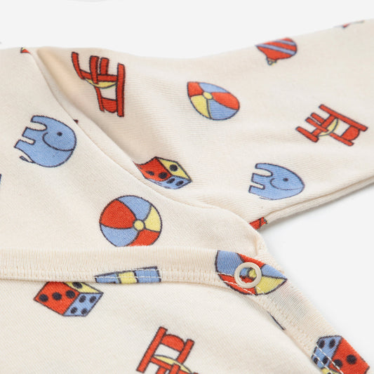 Close-up of a cream-colored fabric with colorful geometric patterns including elephants, circles, and houses.
