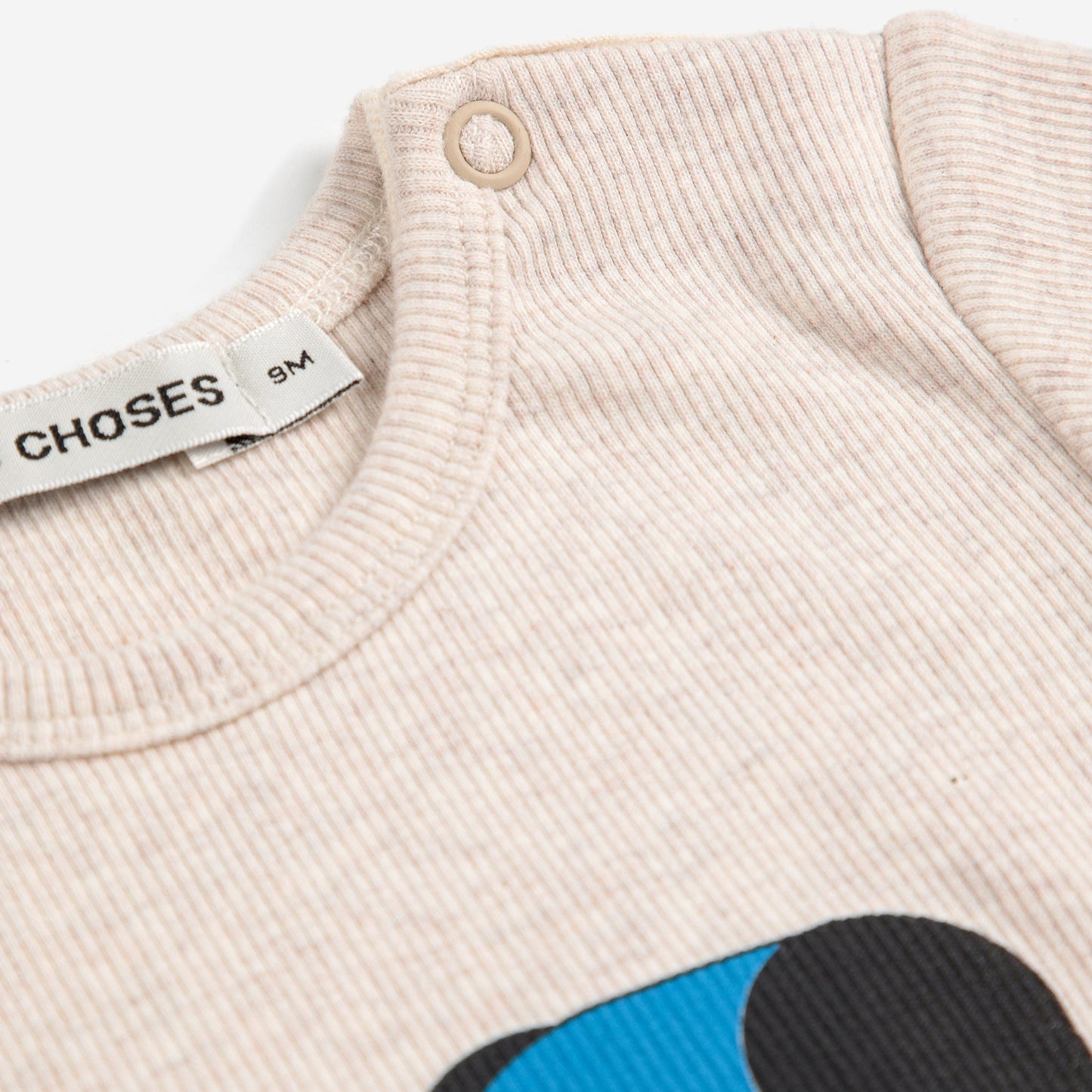 Close-up of a beige sweater with colorful design and 'Choses' label.