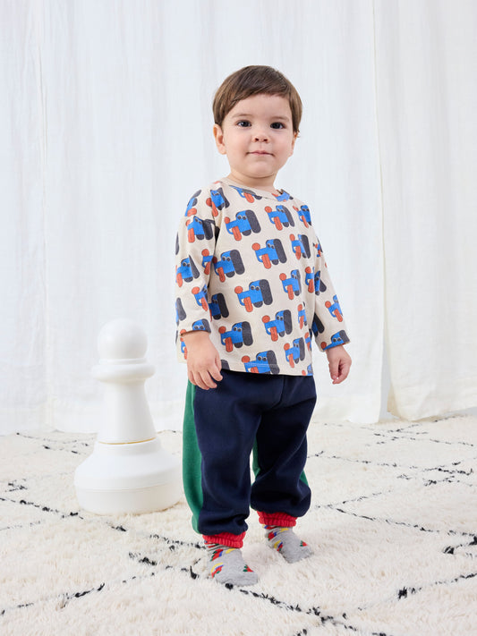 Child wearing a patterned shirt and dark pants on a white background