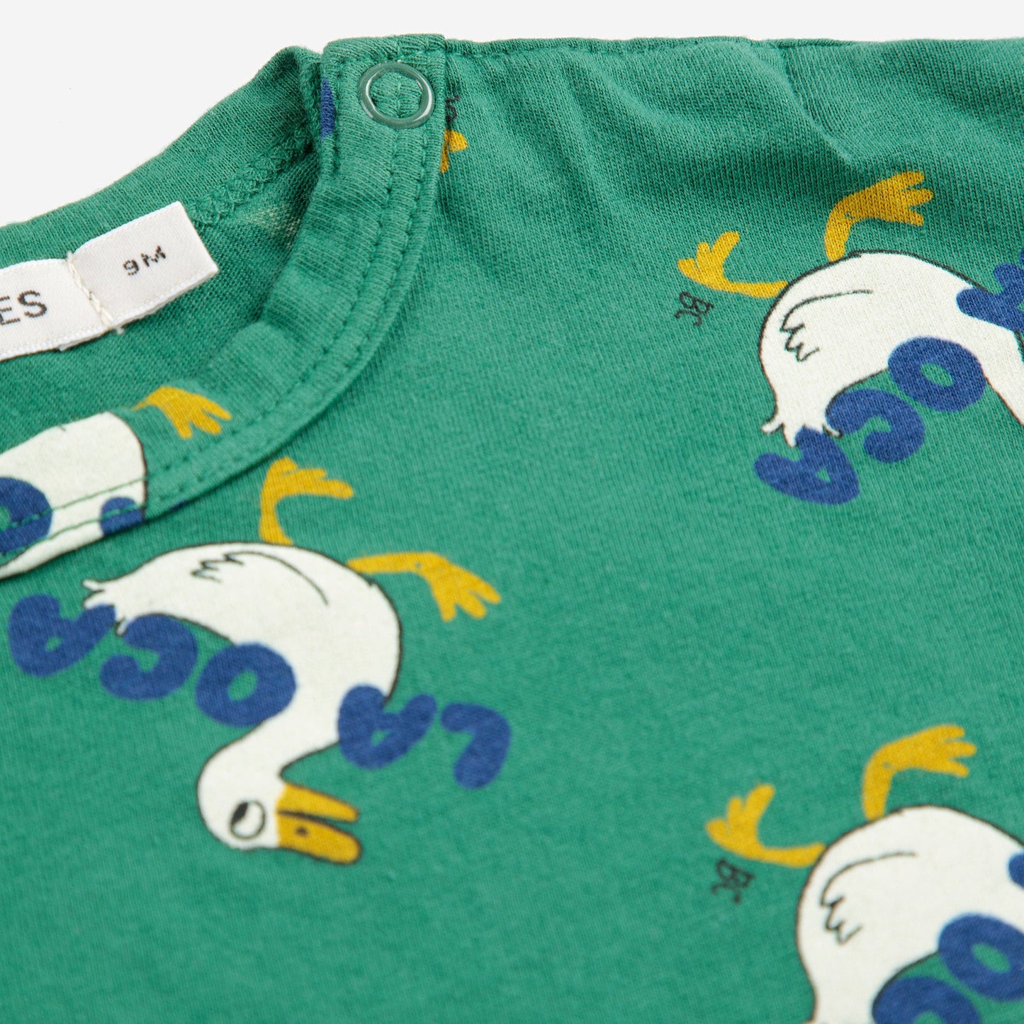 Green fabric with cartoon duck pattern and text on a white background