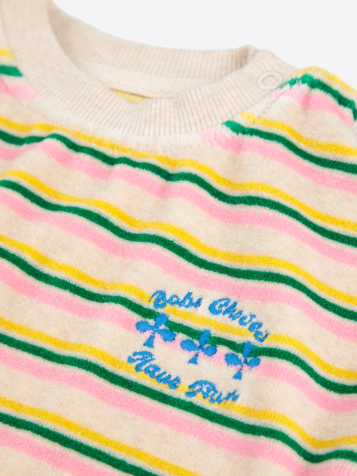 Striped sweater with colorful text and graphics on a beige background