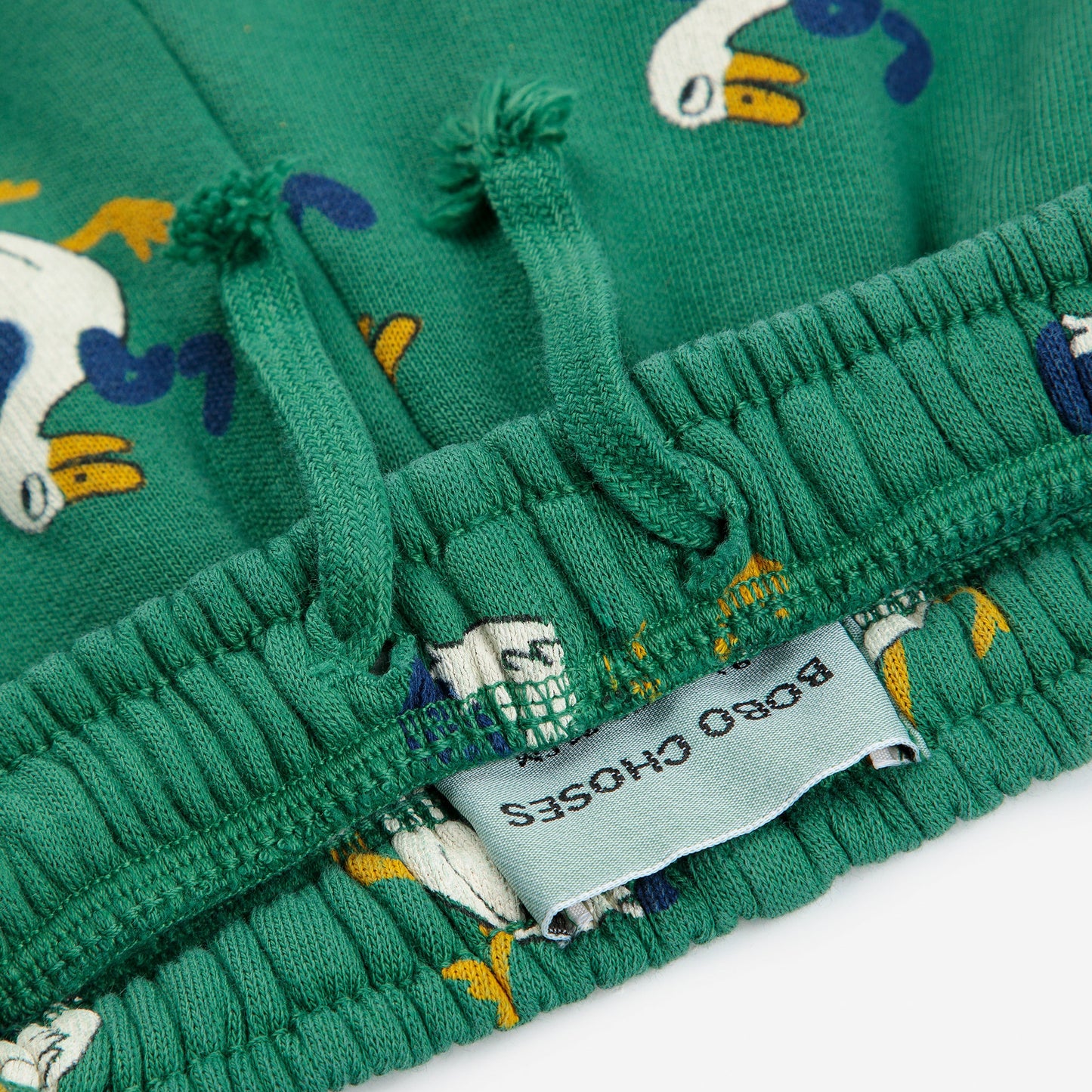Green fabric with cartoon duck pattern and a visible label on a white background