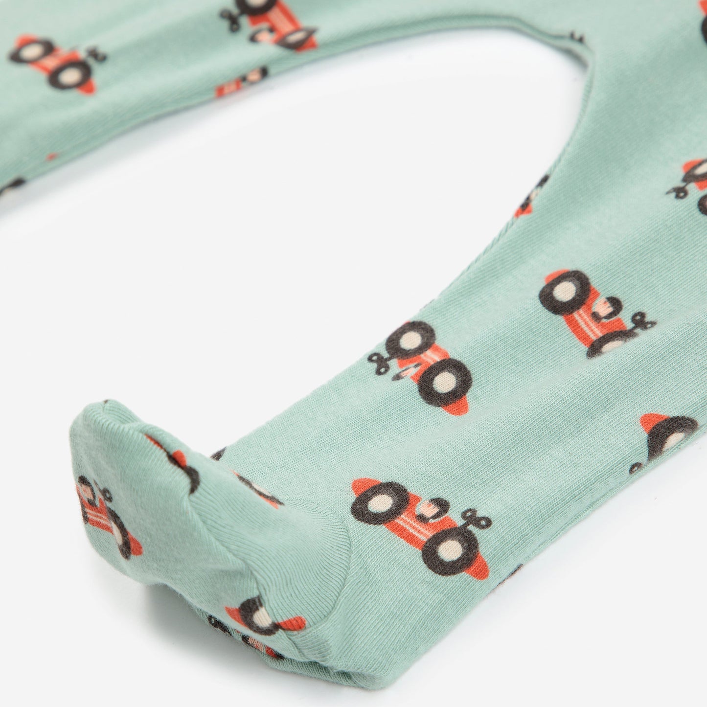 Green fabric with red race car pattern on a white background