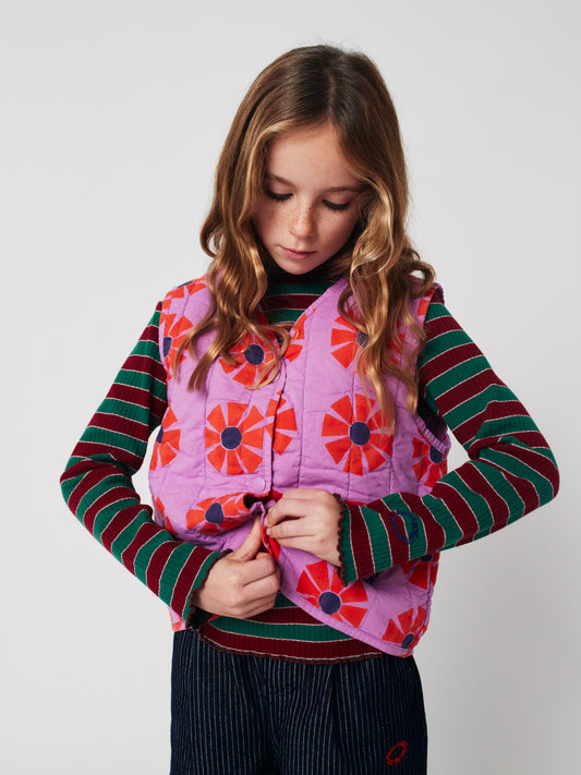 Young girl wearing a colorful quilted vest with a white background
