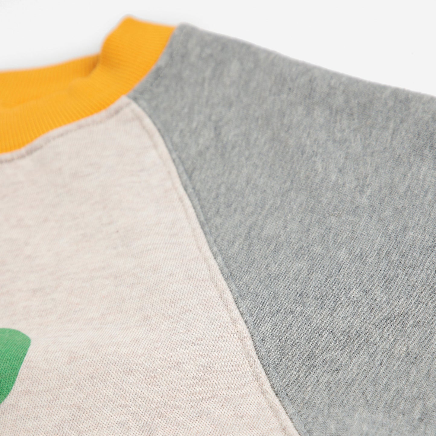 Close-up of a sweater with gray, beige, and yellow sections on a white background