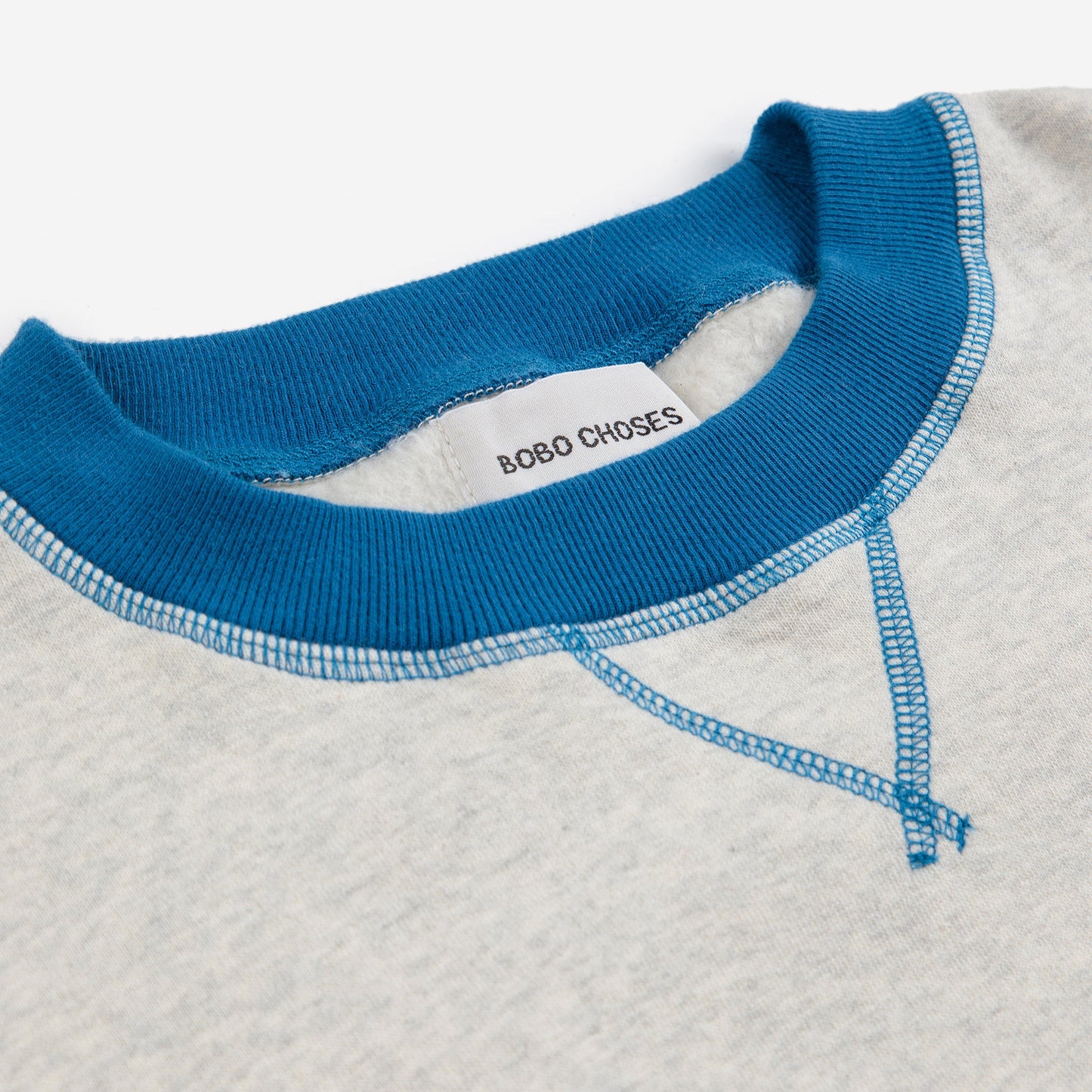 Close-up of a white shirt with blue collar and 'Bobo Choses' label on a white background