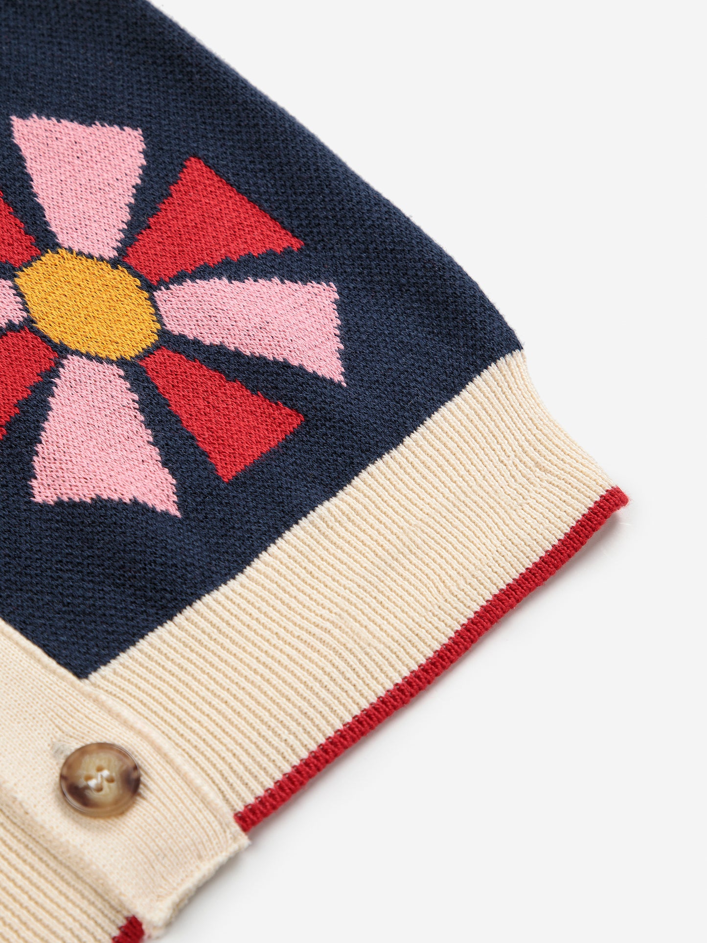 Close-up of a knitted garment with a colorful flower design on a white background