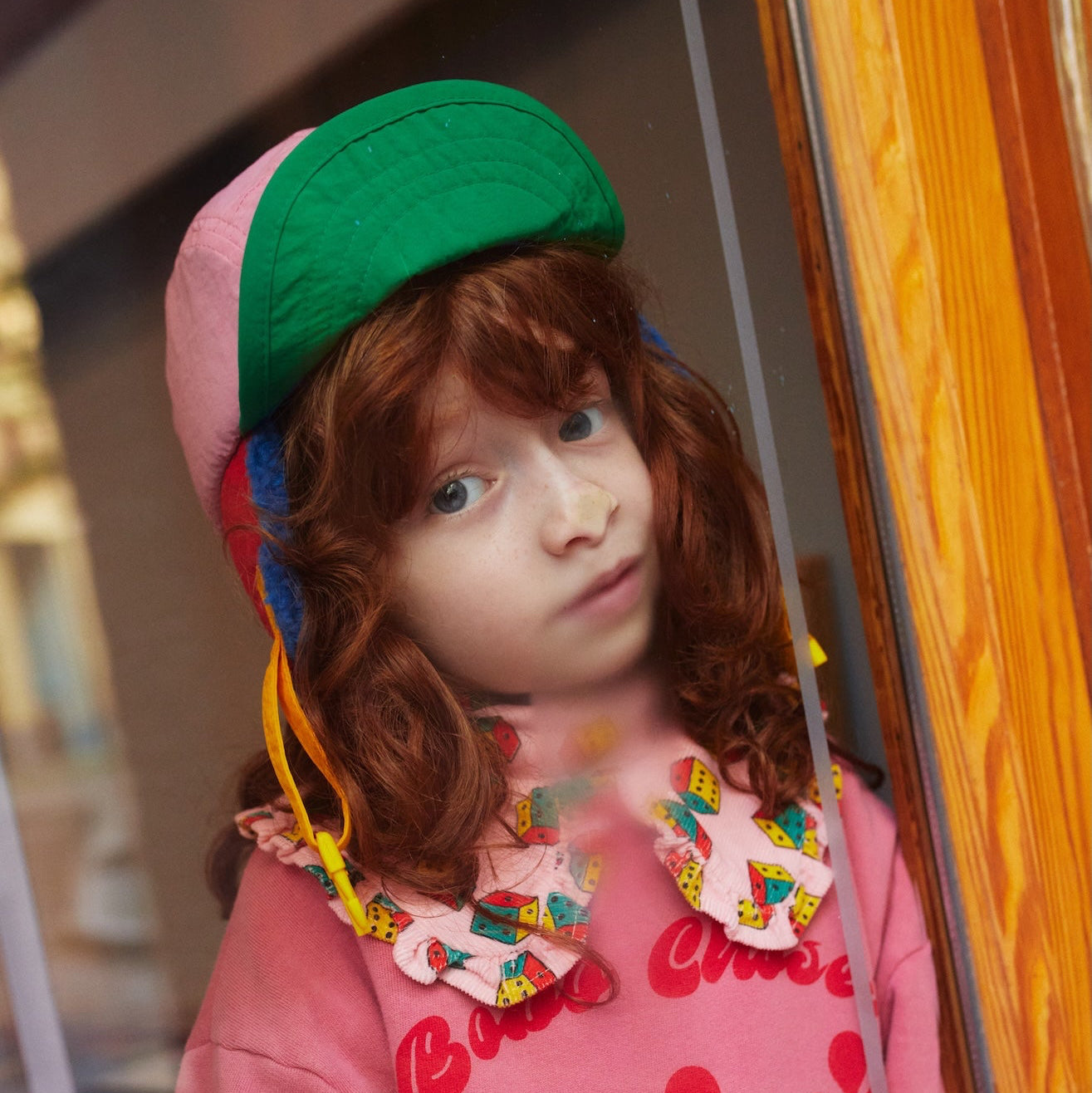 Child wearing a colorful hat and pink sweater with floral design