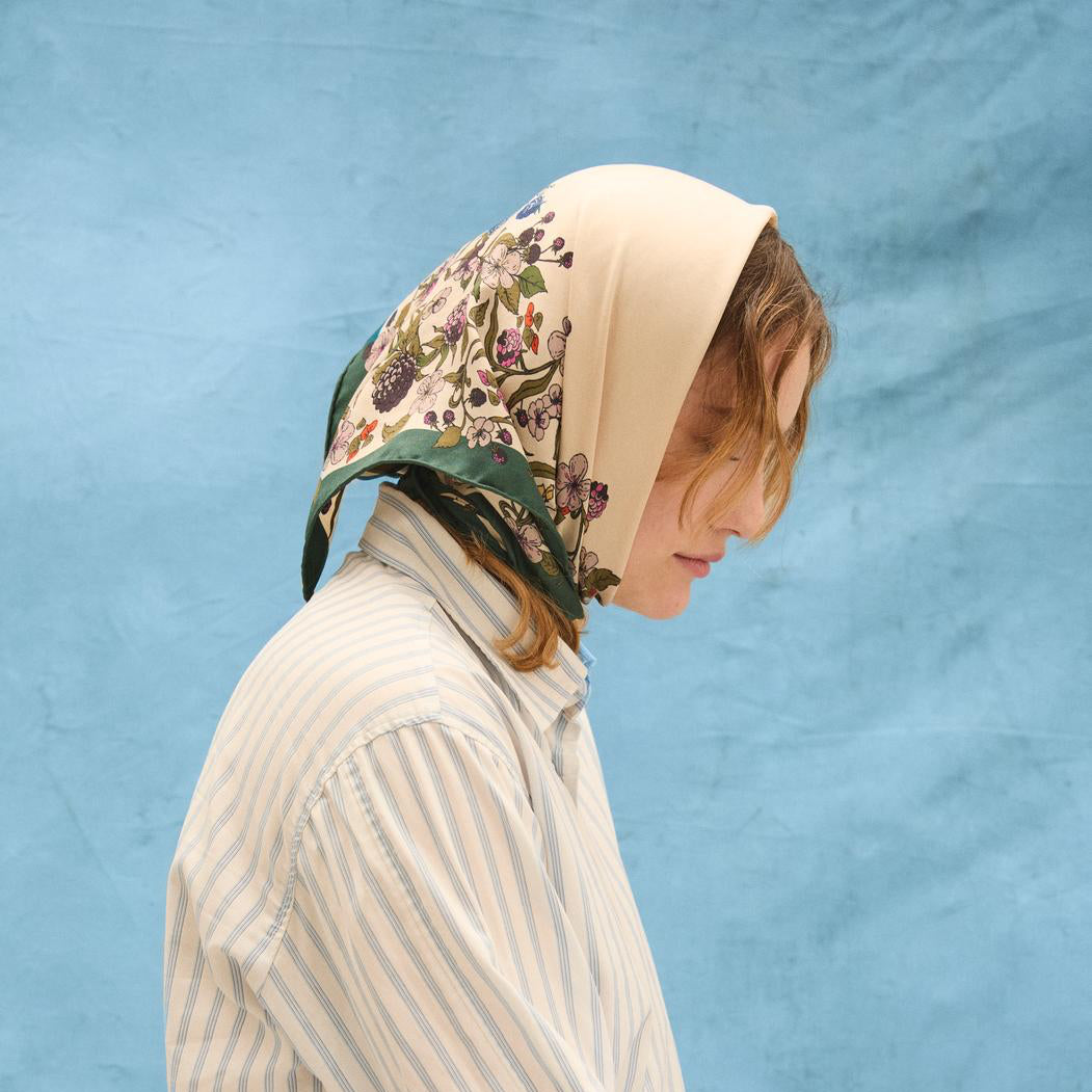 Person wearing a floral-patterned headscarf on a blue background