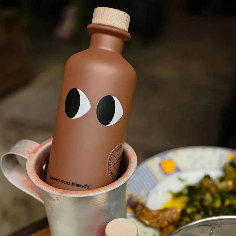 Brown bottle with face design on a table with plates and a cup.