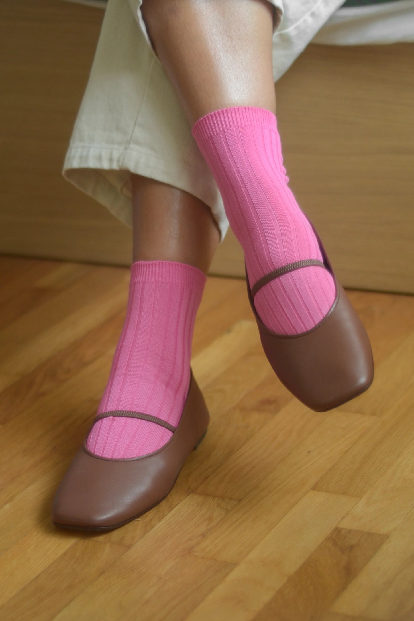 Brown shoes with pink socks on a wooden floor
