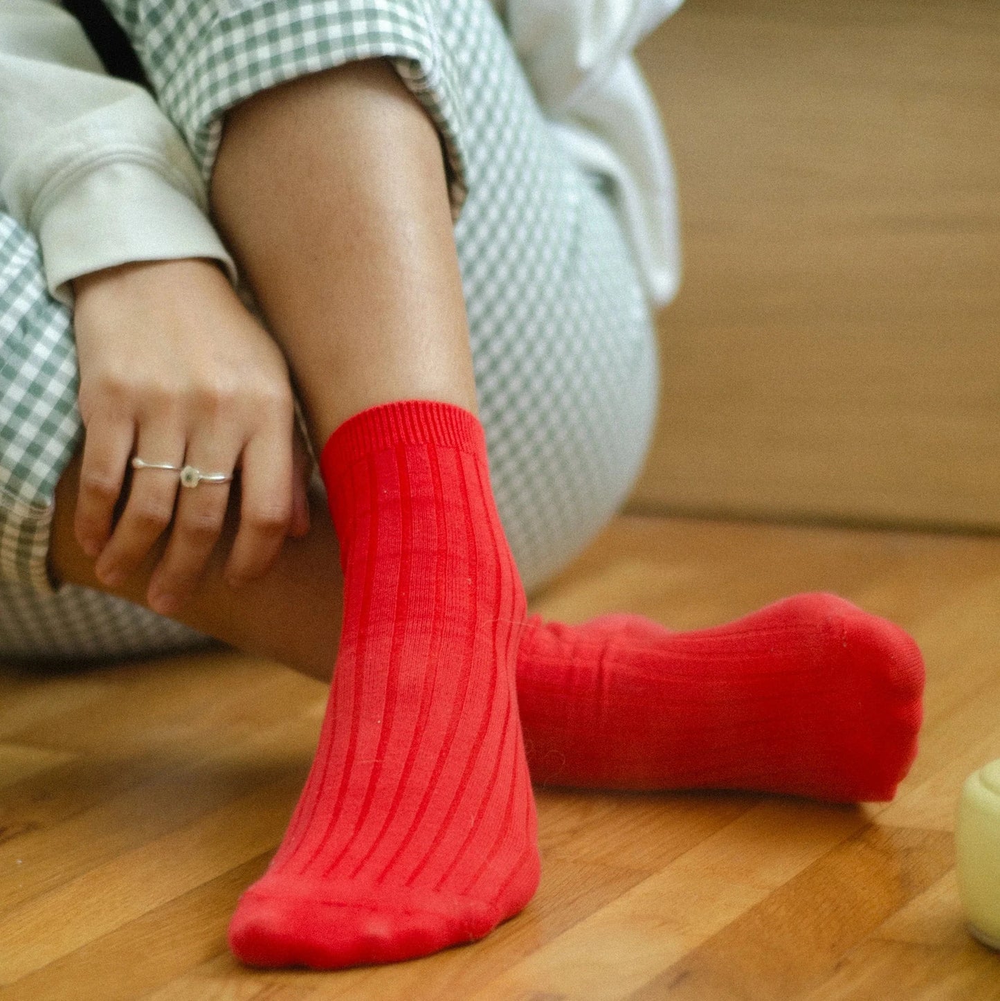 Person wearing red socks sitting on a wooden floor.