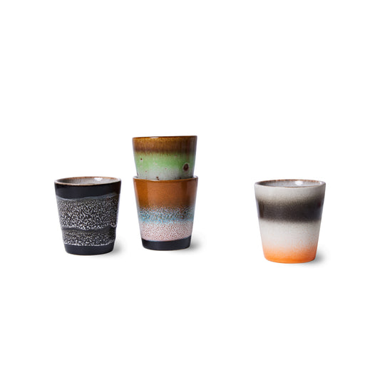 Set of 4 hkliving good vibes ristretto mugs, on a white back drop. The first is black with white natural speckles which fade at the top. Next it two stacked together, the first has a black bottom which fades into a speckled white, then blue to a speckled light drown, then the one of top is mainly lime green which transitions into a deeper brown. Then to the right is the last mug which an orange bottom and chunky cream the black stripes and a white trim