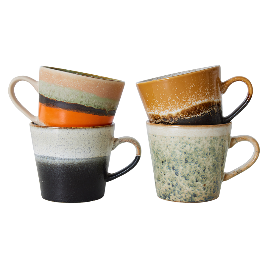 Set of four hkliving verve cappuccino mugs stacked 2by 2. The first is half grey then has a short fade to a speckled white. On top of this one is a mug with half orange and stripes of black and green then cream at the top. Next to these two is a green spackled mug which fades fully to cream at the top. The last one is a dark brown mug with a speckled brown stripe in the middle which fades into a ochre yellow