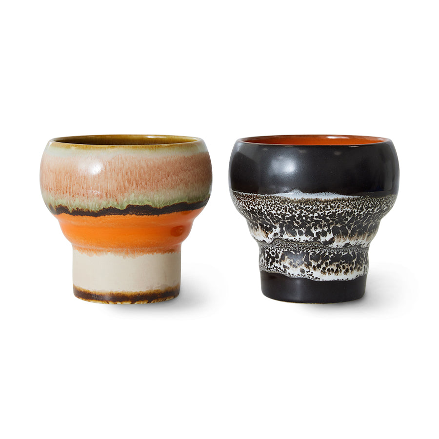 A retro-inspired, curved ceramic mug in earthy, basalt tones from HKliving's 70s ceramics collection. The mug features a smooth, glossy finish with subtle color gradients, showcasing a vintage aesthetic. It is designed with a wide handle and a generous size, perfect for serving lungo coffee. The handmade details give it a unique, artisanal feel, making it both stylish and functional.