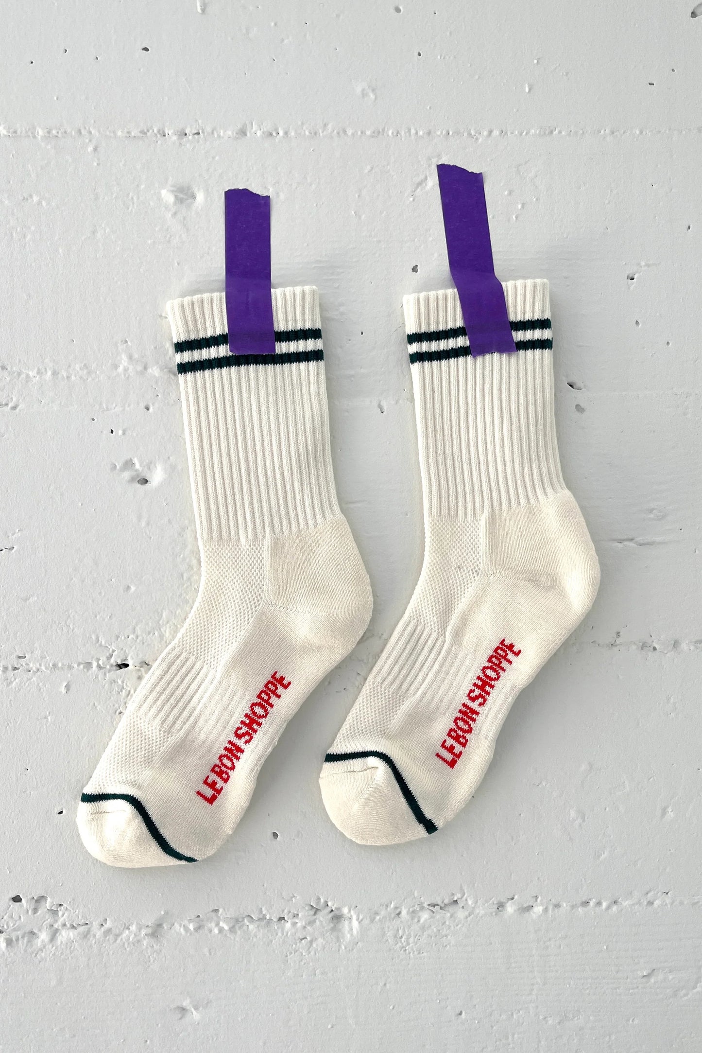 White socks with purple tags and red text on a gray background