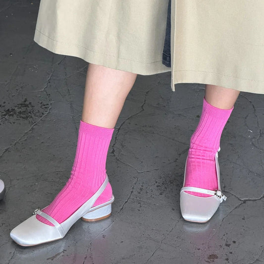 Person wearing pink socks and white shoes on a dark pavement.