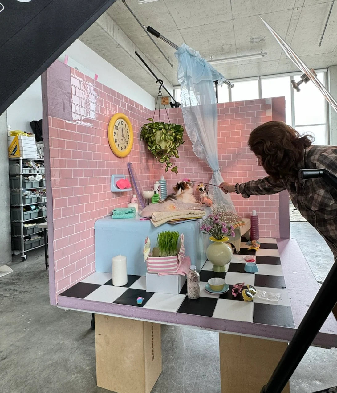 Studio setup with pink tiled wall, checkered floor, and various props.