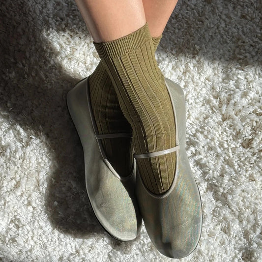 Person wearing green socks and gray shoes on a textured surface