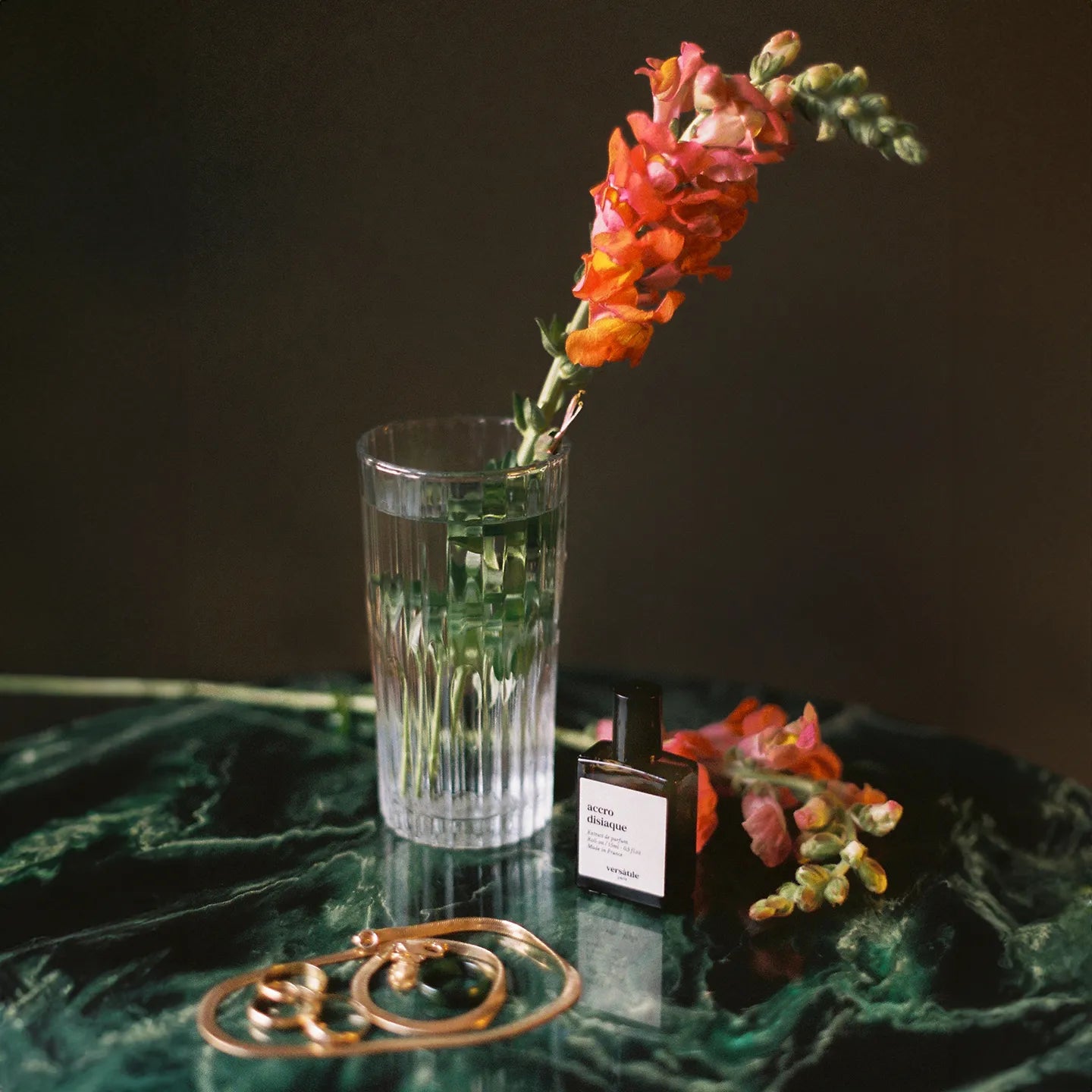 Clear glass with water and flowers on a dark surface