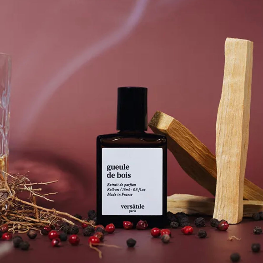 Perfume bottle labeled 'gueule de bois' by Versatèle with wooden elements and berries on a dark background