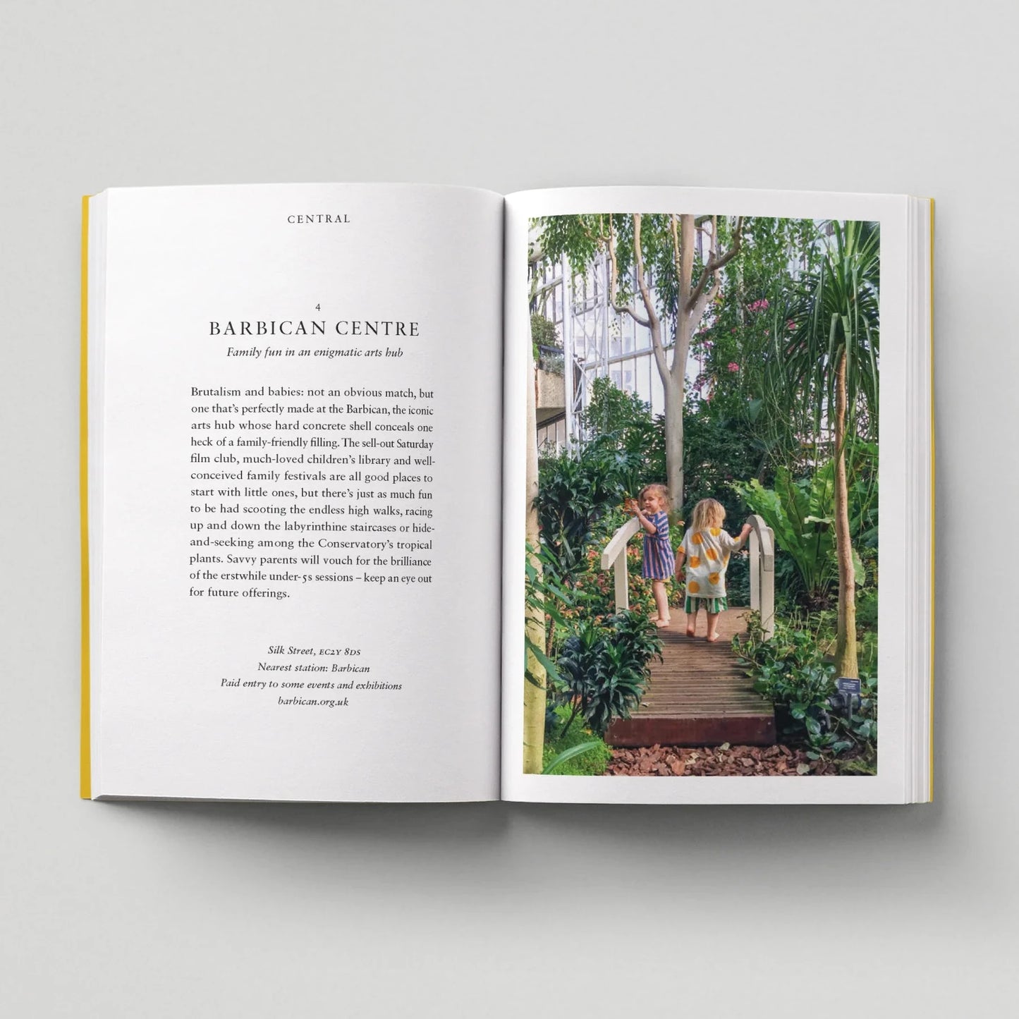 Open book with text on one page and a photograph of two children in a garden on the other, on a light gray background.